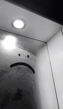 a black and white photo of a sad face with a light above it