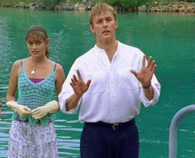 a man and a woman are standing in the water with their hands up