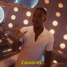 a man in a white shirt says cowards while waving his hand