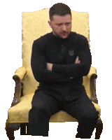 a man is sitting in a chair with his arms crossed and a shirt that says big on it