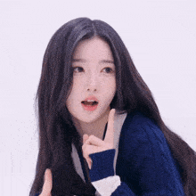 a woman with long black hair wearing a blue sweater