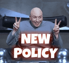 a bald man is giving a peace sign in front of a sign that says " new policy "