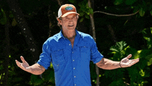 a man wearing a blue shirt and an orange hat is standing with his arms outstretched ..
