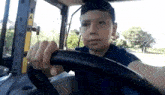 a young boy is driving a tractor with a steering wheel .