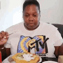 a woman is sitting at a table eating a hamburger .
