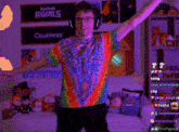 a man in a tie dye shirt is dancing in front of a sign that says twitch rivals