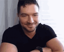 a man wearing a black shirt and a black watch is smiling .
