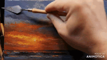 a person is painting a sunset with a spatula and the words made in animotica on the bottom