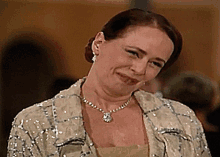a woman wearing a sequined jacket and a necklace makes a funny face