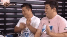 a couple of men are sitting next to each other on a bench .