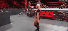 a woman is standing in a wrestling ring with the word raw on the side .