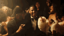 a man in a tuxedo is surrounded by people holding drinks