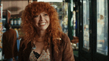 a woman with red hair is smiling in front of a store