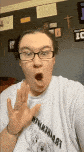 a woman wearing glasses is taking a selfie with her mouth open .