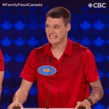 a man in a red shirt with a name tag that says kai on it gives two thumbs up