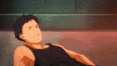 a man in a black tank top laying on the floor
