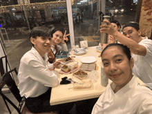 a group of people sitting around a table with plates of food