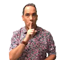 a man in a floral shirt is making a shhh gesture
