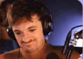 a man wearing headphones is standing in front of a microphone .