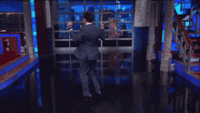 a man in a suit and tie is dancing in front of a window