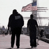 a man wearing a hoodie that says oxygen security walks down a dock