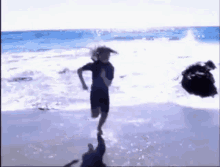 a person is running on a beach with a rock in the background .
