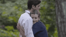 a man and a woman hugging each other in a forest