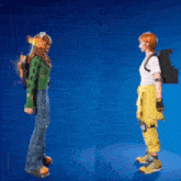a girl in a green sweater and a boy in a yellow jumpsuit are standing next to each other on a blue background