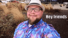 a man wearing a hat and glasses is smiling and says hey friends