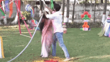 a man and a woman are playing with a hose in a park