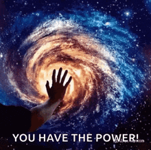 a person 's hand is reaching out towards a spiral galaxy in space .