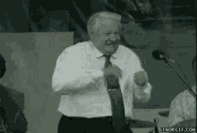 a man in a tie is dancing in front of a microphone .