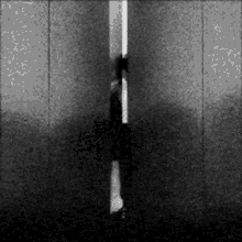 a black and white photo of a person standing in front of a wall .
