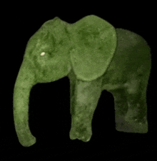 a green stuffed elephant is sitting on a black surface .
