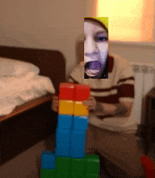 a person playing with a stack of blocks with a picture of their face behind them