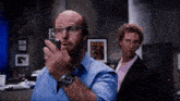a man wearing glasses is talking on a walkie talkie while another man looks on