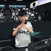 a young boy wearing a kia shirt stands in front of a crowd