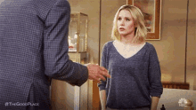 a woman in a blue sweater is standing next to a man in a plaid suit .