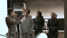a group of people are standing in a room with a man pointing