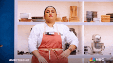 a woman in an apron stands in front of a nbc logo