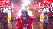 a wrestler in a red and blue costume is standing in a ring with fireworks coming out of his mouth .