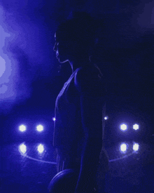 a close up of a woman 's face in a dark room with a blue light behind her