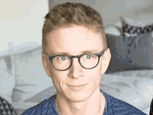 a man wearing glasses and a blue shirt is smiling for the camera