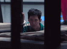 a man is looking out of a prison cell .