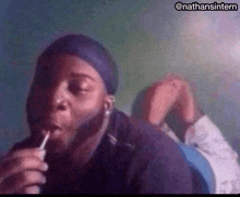 a man is laying on his stomach smoking a pipe .