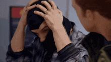 a man with a ring on his finger is putting a mask on another man 's head