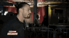 a man in a black shirt with a wwe.com exclusive sticker on his chest