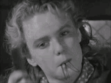 a close up of a person 's face with a clock in his mouth .