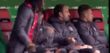 a group of men are sitting in a stadium watching a soccer game .