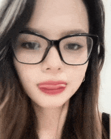 a close up of a woman wearing glasses with her tongue sticking out